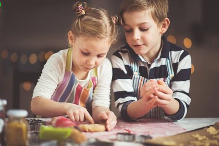 Happy little siblings children preparing Christmas cookies at homeの写真素材