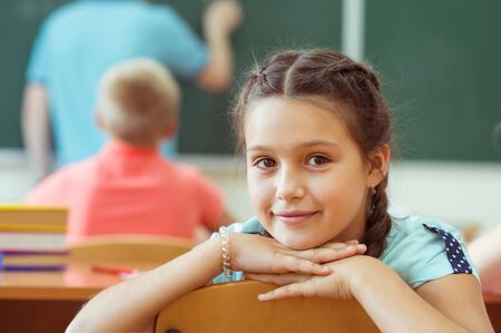 Cute smiling schoolgirl at school during lessonの写真素材
