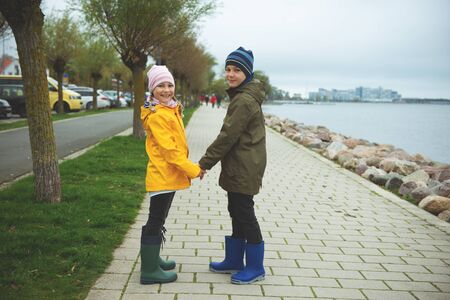 Teen brother and sister walking on Baltic coastline in high rubber boots and colorful jackets in northern Germanyの写真素材