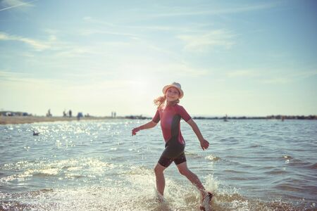 Happy pretty teen girl in neoprene swimingsuit  playing and running in Baltic seaの写真素材