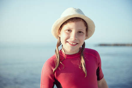 Portrait of teen child girl in white hat in water in Baltic sea