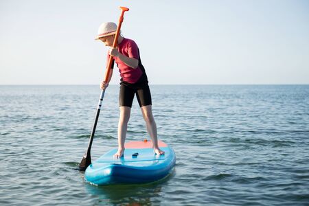 Happy teen child girl paddling on sup board in Baltic seaの写真素材
