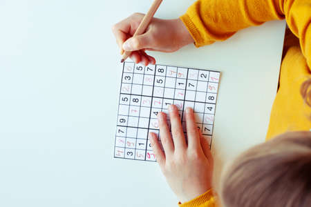 Adorable teen girl solving sudoku at desk at school or at home. View from aboveの写真素材