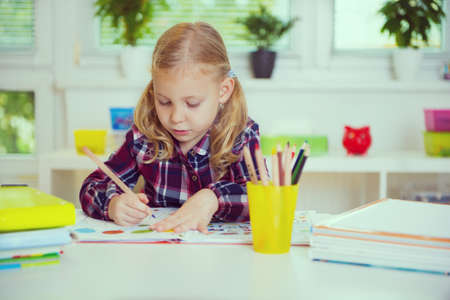 Portrait of pretty school girl in yellow are studying at classroom at the tableの写真素材