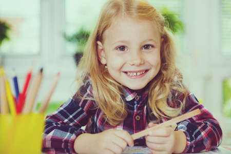 Portrait of pretty school girl in yellow are studying at classroom at the tableの写真素材
