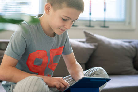 Cute blond teen study with tablet at home during coronavisrus lockdownの写真素材
