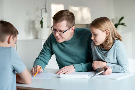 Young father helping his children with homeschooling during covid-19 lockdownの写真素材