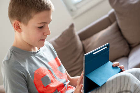 Cute blond teen study with tablet at home during coronavisrus lockdownの写真素材