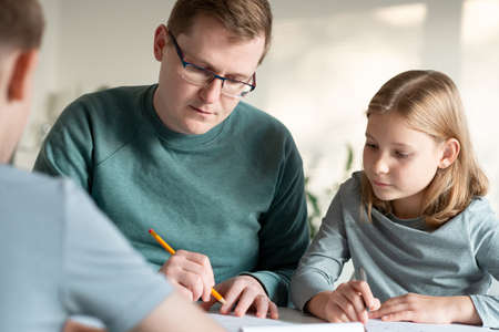 Young father helping his children with homeschooling during covid-19 lockdown