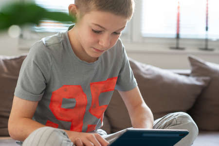 Cute blond teen study with tablet at home during coronavisrus lockdownの写真素材
