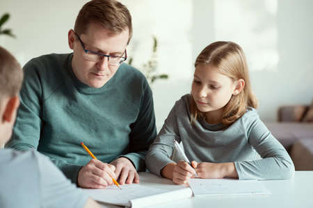 Young serious father at home office teaching his children during quarantine lockdown at homeの写真素材