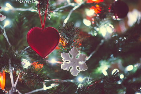 Close up photo of christmas tree decorated with balls, red hearts in darkness but with christmas lights at new years eveの写真素材
