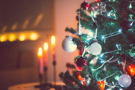 Close up photo of christmas tree decorated with balls, red hearts in darkness but with christmas lights at new years eveの写真素材