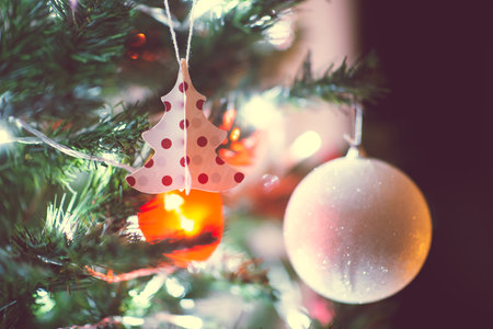 Close up photo of christmas tree decorated with balls, red hearts in darkness but with christmas lights at new years eveの写真素材