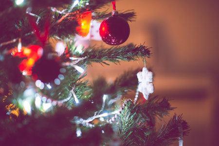 Close up photo of christmas tree decorated with balls, red hearts in darkness but with christmas lights at new years eveの写真素材