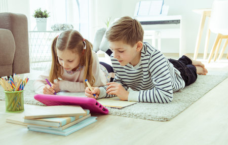 Cute siblings schoolchildren studying at home office during  quarantineの写真素材