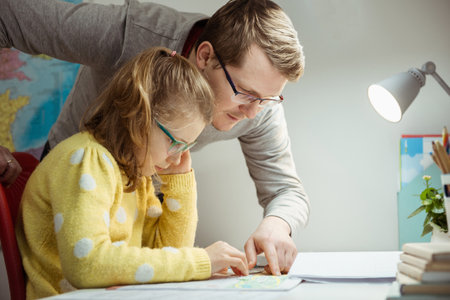 Young father teaching and helping his daughter with homework during pandemic quarantine homeschoolingの写真素材