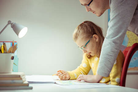 Young father teaching and helping his daughter with homework during pandemic quarantine homeschoolingの写真素材