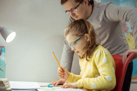 Young father teaching and helping his daughter with homework during pandemic quarantine homeschoolingの写真素材