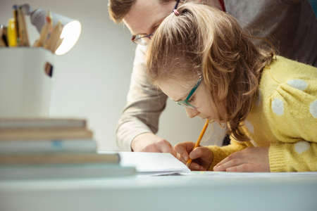 Young father teaching and helping his daughter with homework during pandemic quarantine homeschoolingの写真素材