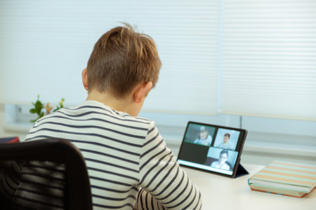 Teenager school boy having virtual lesson at home using tablet during homeschooling at pandemic quarantineの写真素材