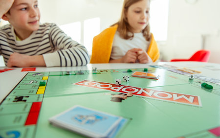 KIEL, GERMANY - February 14, 2021: Happy children having fun playing board game in cozy family time evening together with their parentsのeditorial素材