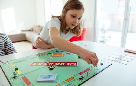 KIEL, GERMANY - February 14, 2021: Happy children having fun playing board game in cozy family time evening together with their parentsのeditorial素材
