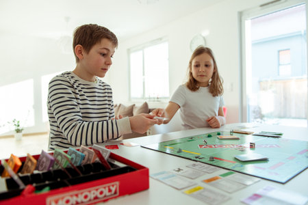 KIEL, GERMANY - February 14, 2021: Happy children having fun playing board game in cozy family time evening together with their parentsのeditorial素材