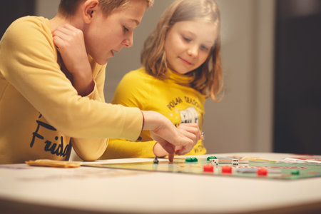 KIEL, GERMANY - 07 December 2020: Happy children having fun playing board game in cozy family time evening together with their parentsのeditorial素材