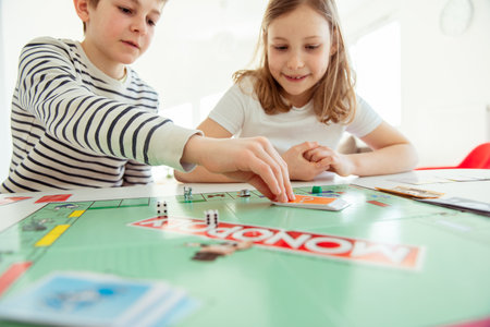 KIEL, GERMANY - February 14, 2021: Happy children having fun playing board game in cozy family time evening together with their parentsのeditorial素材