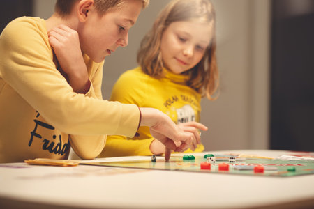 KIEL, GERMANY - 07 December 2020: Happy children having fun playing board game in cozy family time evening together with their parentsのeditorial素材