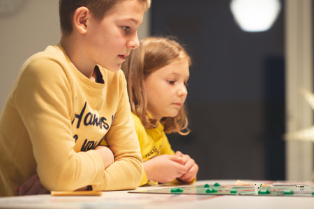 KIEL, GERMANY - 07 December 2020: Happy children having fun playing board game in cozy family time evening together with their parentsのeditorial素材
