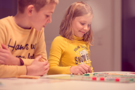 KIEL, GERMANY - 07 December 2020: Happy children having fun playing board game in cozy family time evening together with their parentsのeditorial素材