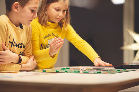 KIEL, GERMANY - 07 December 2020: Happy children having fun playing board game in cozy family time evening together with their parentsのeditorial素材