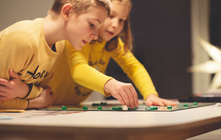 KIEL, GERMANY - 07 December 2020: Happy children having fun playing board game in cozy family time evening together with their parentsのeditorial素材