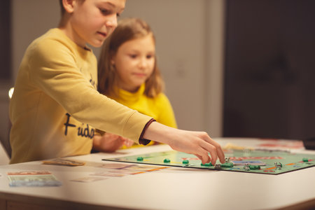 KIEL, GERMANY - 07 December 2020: Happy children having fun playing board game in cozy family time evening together with their parentsのeditorial素材