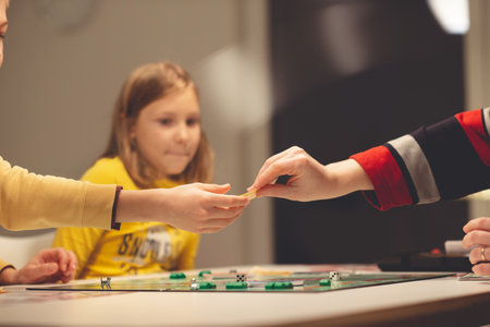 KIEL, GERMANY - 07 December 2020: Happy children having fun playing board game in cozy family time evening together with their parentsのeditorial素材