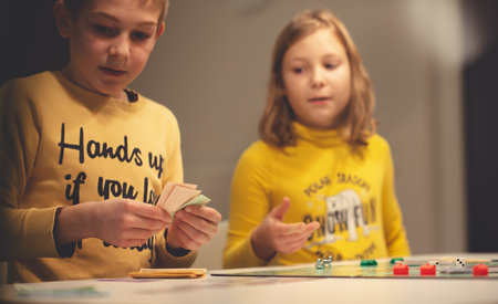 KIEL, GERMANY - 07 December 2020: Happy children having fun playing board game in cozy family time evening together with their parentsのeditorial素材