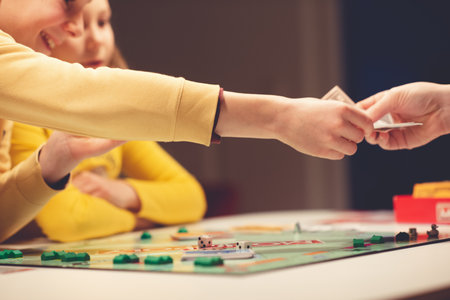 KIEL, GERMANY - 07 December 2020: Happy children having fun playing board game in cozy family time evening together with their parentsのeditorial素材