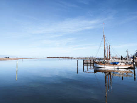 Beautiful photo of modern and old fishing boats in harbor near wooden pier in calm sunset lightの写真素材