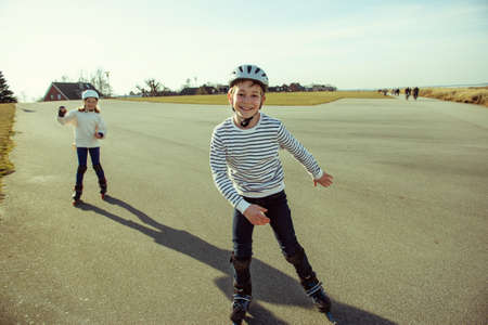 Happy siblings teenager boy and girl having fun during inline skating at sunny summer day at Baltic sea promenadeの写真素材