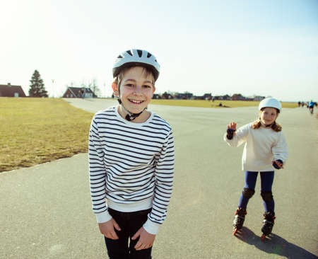 Happy siblings teenager boy and girl having fun during inline skating at sunny summer day at Baltic sea promenadeの写真素材