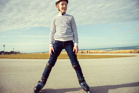 Happy teenager boy in helmet, inline skates and safety equipment is happy learning skating sunny day in summerの写真素材