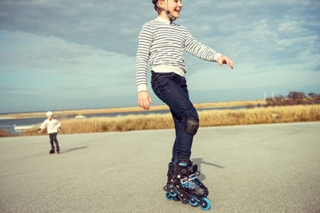 Happy siblings teenager boy and girl having fun during inline skating at sunny summer day at Baltic sea promenadeの写真素材