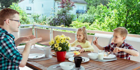 Happy young family having fun during breakfast on the big terrasse at homeの写真素材