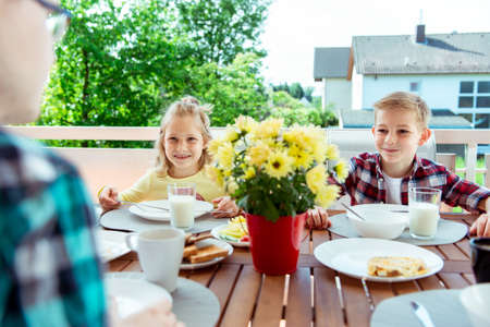 Happy young family having fun during breakfast on the big terrasse at homeの写真素材