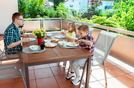 Happy young family having fun during breakfast on the big terrasse at homeの写真素材