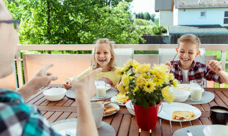 Happy young family having fun during breakfast on the big terrasse at homeの写真素材
