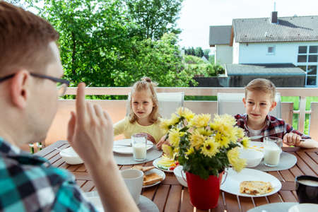 Happy young family having fun during breakfast on the big terrasse at homeの写真素材