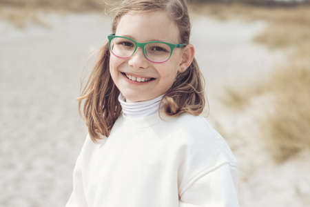 Portrait of cute teenage girl in glasses smiling and posing on bech with dunes on Baltic seaの写真素材